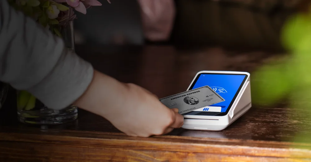 Square公式写真。カウンターに置いたSquare ターミナルの画面へ、お客さまがカードをかざしている。